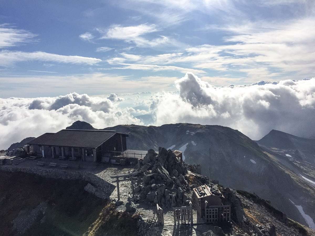 立山頂上から雄山神社峰本社の社務所と雄大な景色を望む